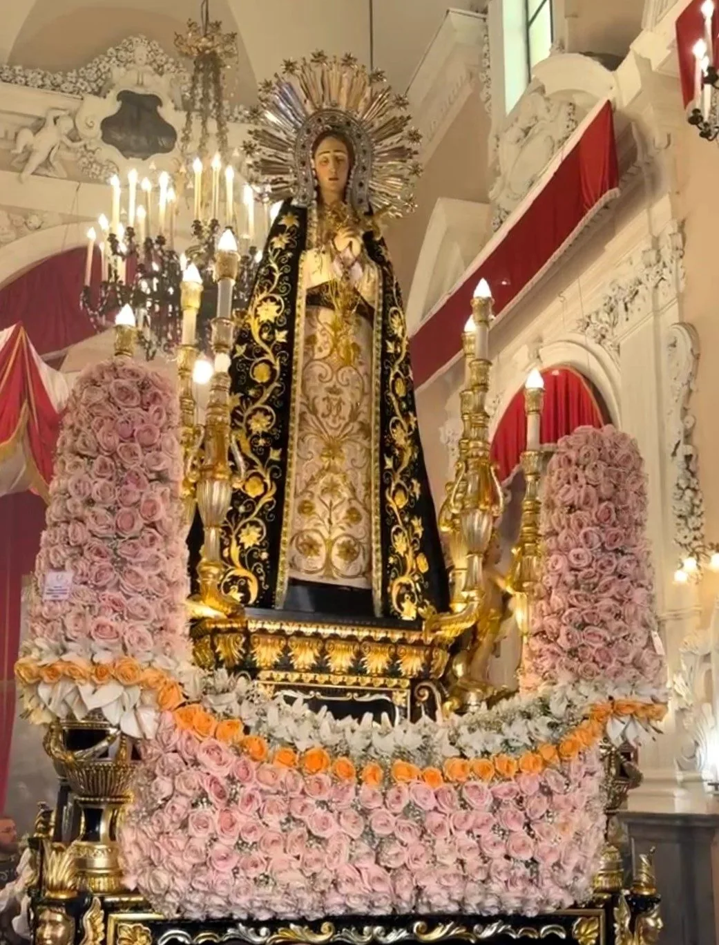 La statua dell'Addolorata sulla vara decorata di rose e candele, pronta per la processione del Venerdì Santo a Palermo