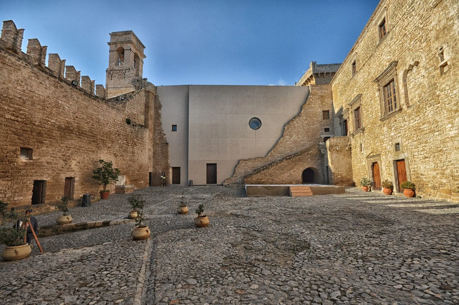 Cortile acciottolato del Castello La Grua-Talamanca di Carini con mura merlate e campanile